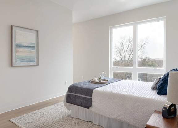 A bedroom with a bed, a nightstand, and a window.