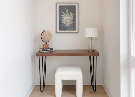 A white chair sits in front of a table with a globe and lamp on it.