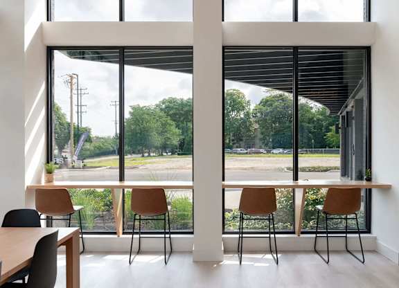 A room with a table and chairs in front of a large window with a view of the outside.