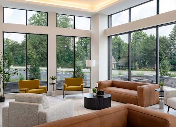 A living room with a large window and a view of trees and a road.