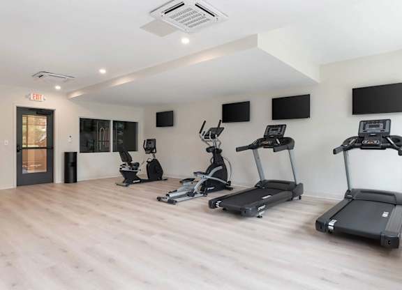 A gym with treadmills, elliptical machines, and other exercise equipment.