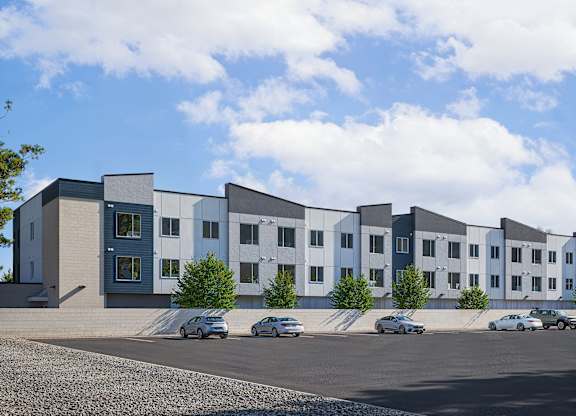 A row of modern buildings with cars parked in front.