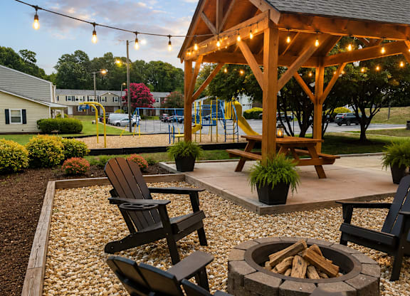 A wooden pavilion with a fire pit and chairs in the foreground.