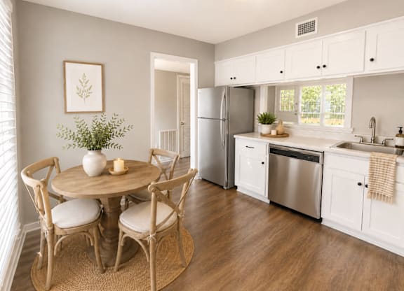 A kitchen with a table and chairs in the foreground and a refrigerator in the background.