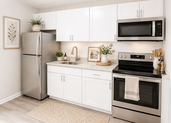 A modern kitchen with white cabinets and stainless steel appliances.
