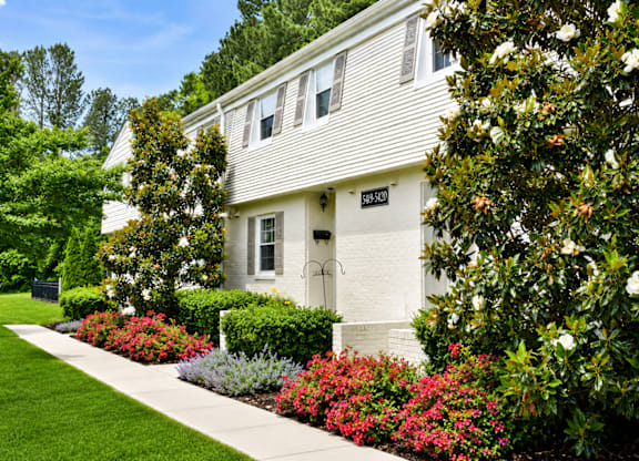 A white house with a garden in front.