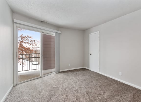 an empty living room with a sliding glass door to a balcony at Eastwood Crossings, Kansas City, Missouri