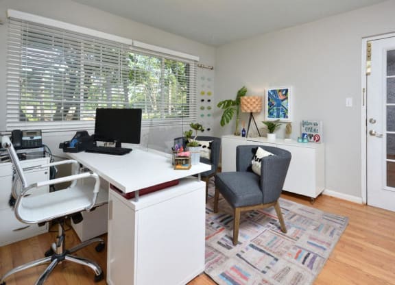 a home office with a large window and a desk with a computer at Parkside at Five Points Apartments, Raleigh