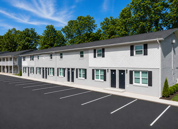 A long building with a parking lot in front.