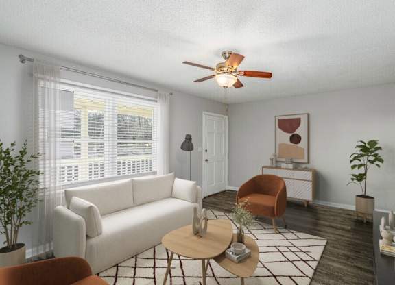 A living room with a white couch, a brown chair, a coffee table, and a ceiling fan.