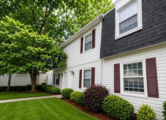 A white house with a black roof and red shutters.