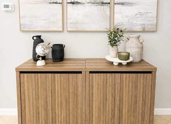 A wooden cabinet with three vases on top of it.