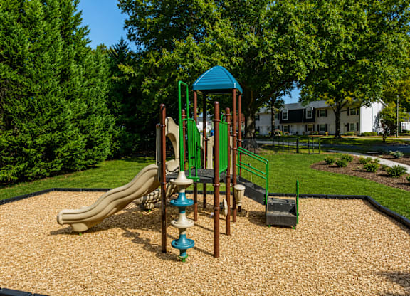 A playground with a slide, swings, and a playhouse.