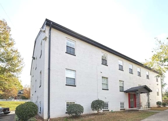 a white brick building with a red door at Viceroy Apartments, Durham , NC 27707