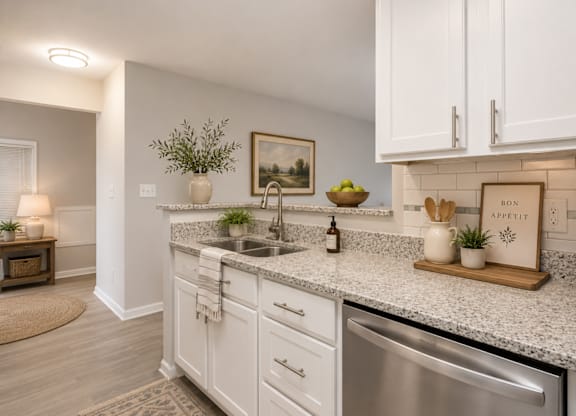 A kitchen with white cabinets and a marble countertop.