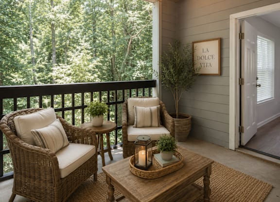 A cozy balcony with a wicker chair, a sofa, a coffee table, and a potted plant.