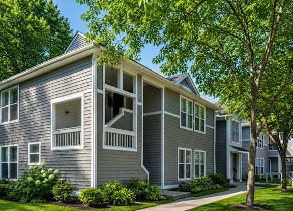 A grey two story house with a tree in front.