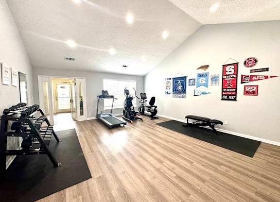 A gym with a variety of equipment including treadmills, weights, and exercise machines.