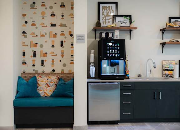 A kitchen with a blue couch and a wall with a pattern of shapes at Hudson at Renaissance Apartments, Wilmington, North Carolina