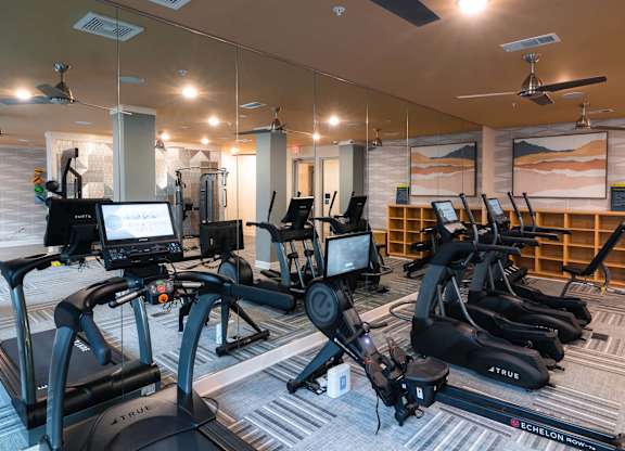 A gym with a variety of exercise equipment including treadmills and stationary bikes at Hudson at Renaissance Apartments, Wilmington, NC 28405