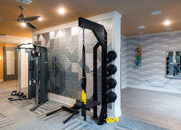 A home gym with a squat rack, weights, and a mirror at Hudson at Renaissance Apartments, Wilmington, NC