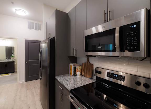 A modern kitchen with a black refrigerator and stainless steel appliances at Hudson at Renaissance Apartments, North Carolina 28405