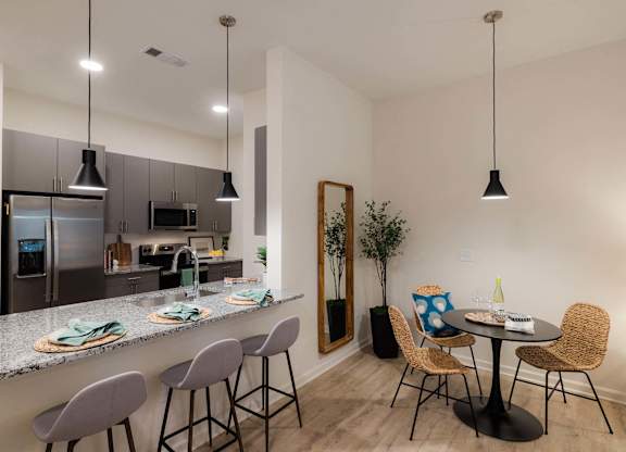 A kitchen with a bar area and a dining table with chairs at Hudson at Renaissance Apartments, Wilmington, NC