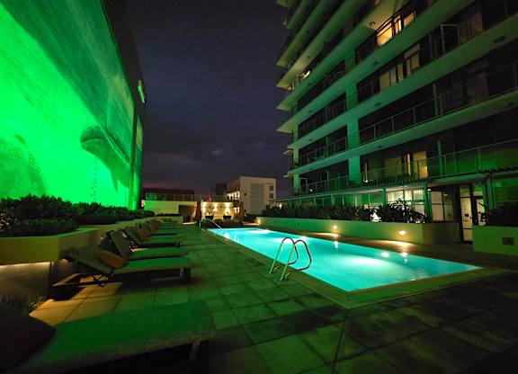 A pool with lounge chairs and a building in the background.