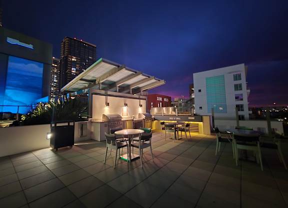 A rooftop patio with a table and chairs under a sky lit by the setting sun.