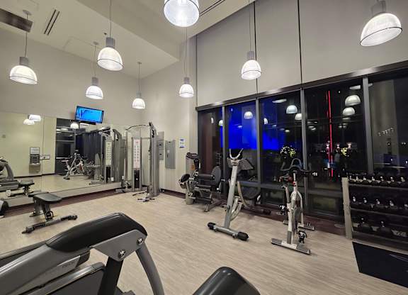 A gym with a variety of equipment including treadmills, weights, and exercise machines.