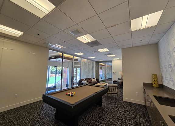 A pool table in a room with a window.
