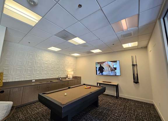 A room with a pool table and a television.