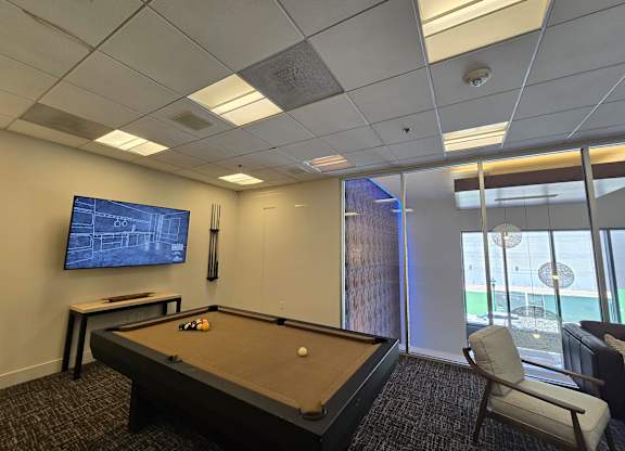 A pool table in a room with a television and a chair.