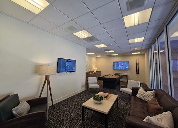 A living room with a brown couch, a coffee table, and a flat screen TV mounted on the wall.