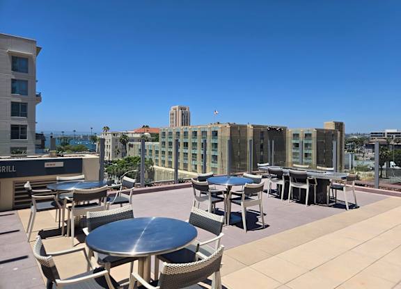 A patio with tables and chairs overlooking a cityscape.
