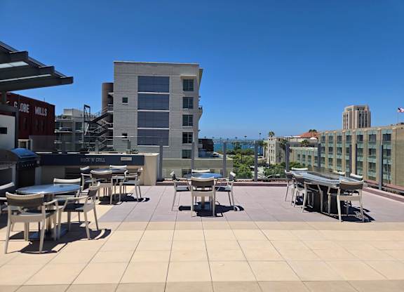 A rooftop patio with tables and chairs overlooking a cityscape.