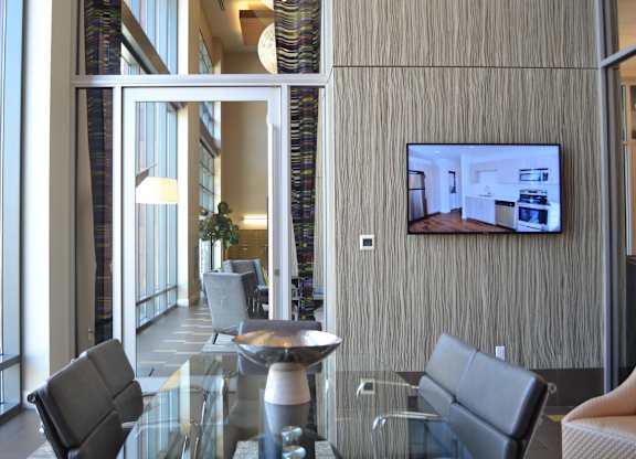 A modern living room with a glass table and a television on the wall.