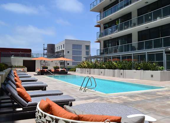 A pool area with lounge chairs and a building in the background.