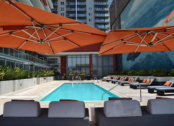 A pool surrounded by orange umbrellas and lounge chairs.