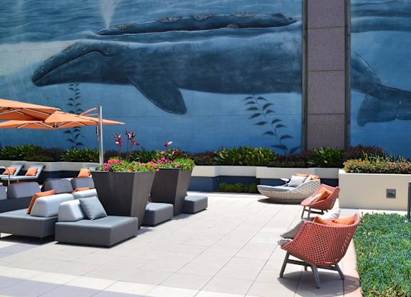 A whale mural is on the wall behind a patio with chairs and tables.