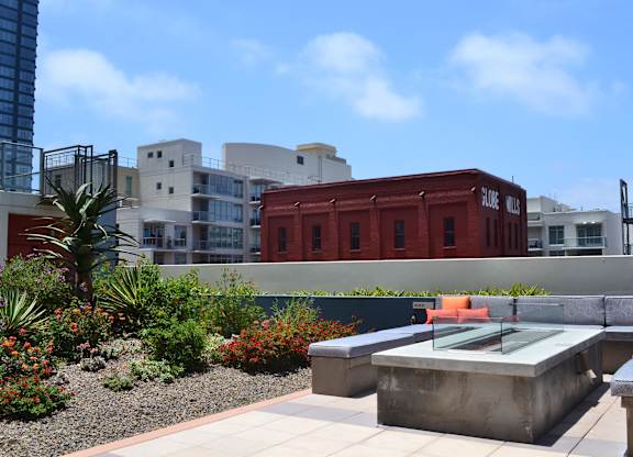 A red shipping container sits in the middle of a courtyard with a table and chairs.
