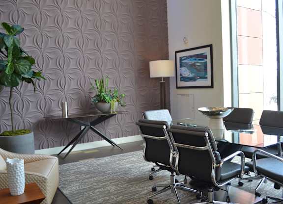 A conference room with a table, chairs, and a painting on the wall.