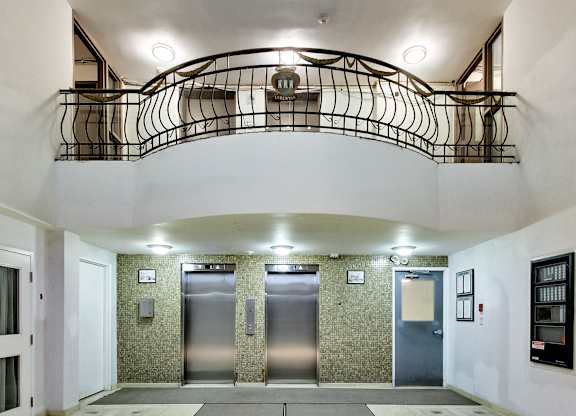 A hallway with a staircase and three elevators.