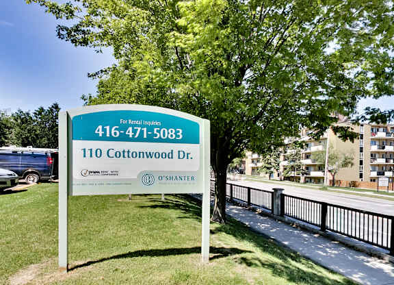 A sign for 110 Cottonwood Dr. is displayed in front of a tree.