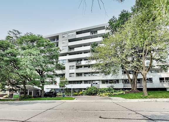 a large white apartment building with trees in front of it