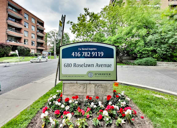 a sign on the side of a street next to some flowers