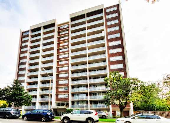A large apartment building with cars parked in front.