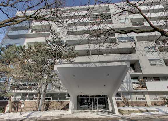 the front of an apartment building with a white facade and trees
