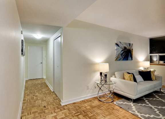 A living room with a white couch and a painting on the wall.