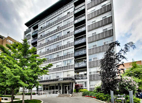 an apartment building with a driveway and trees in front of it